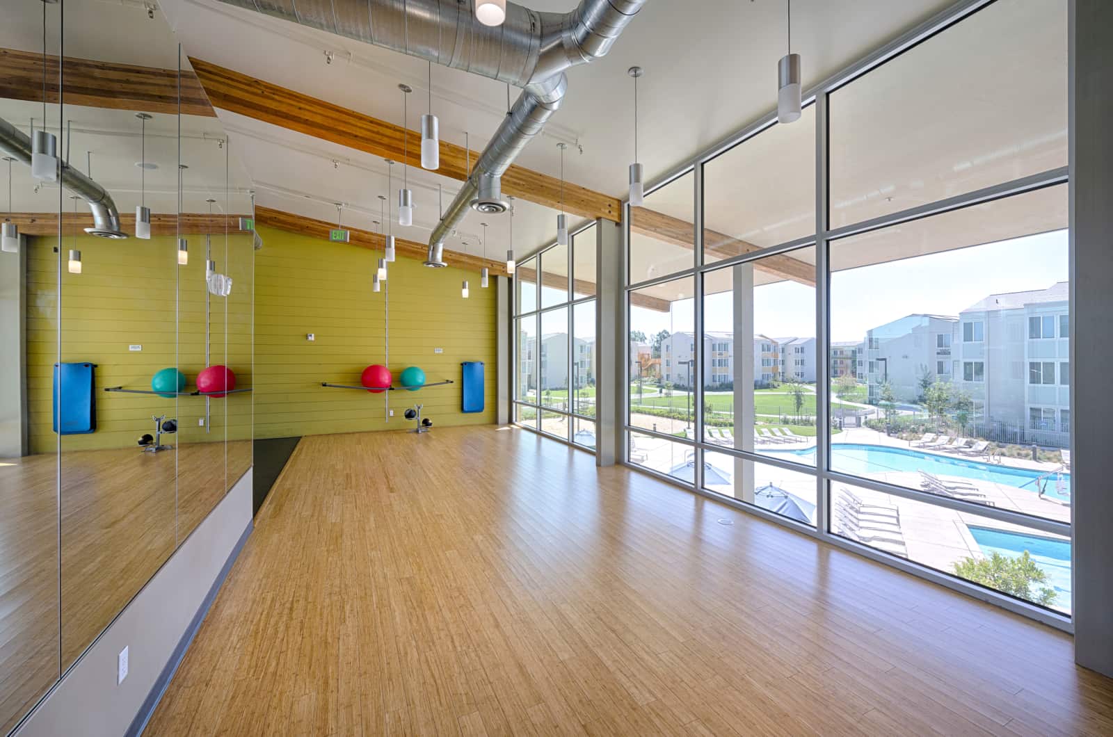 View of empty fitness room with bamboo floors and large windows.