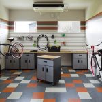 Interior of a bike repair room with workbench, tool cabinets, various tools and two bikes on stands.