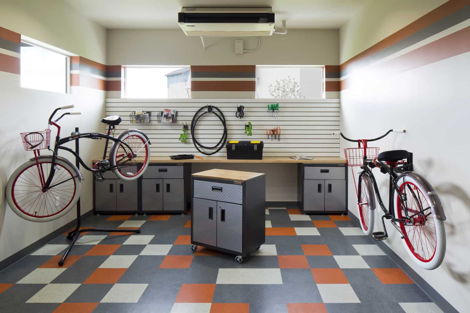 Interior of a bike repair room with workbench, tool cabinets, various tools and two bikes on stands.