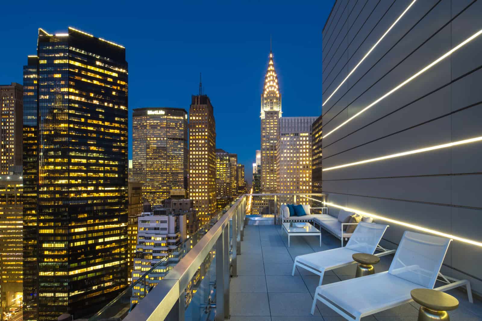 Exterior of large balcony with seating amidst downtown New York skyscrapers.