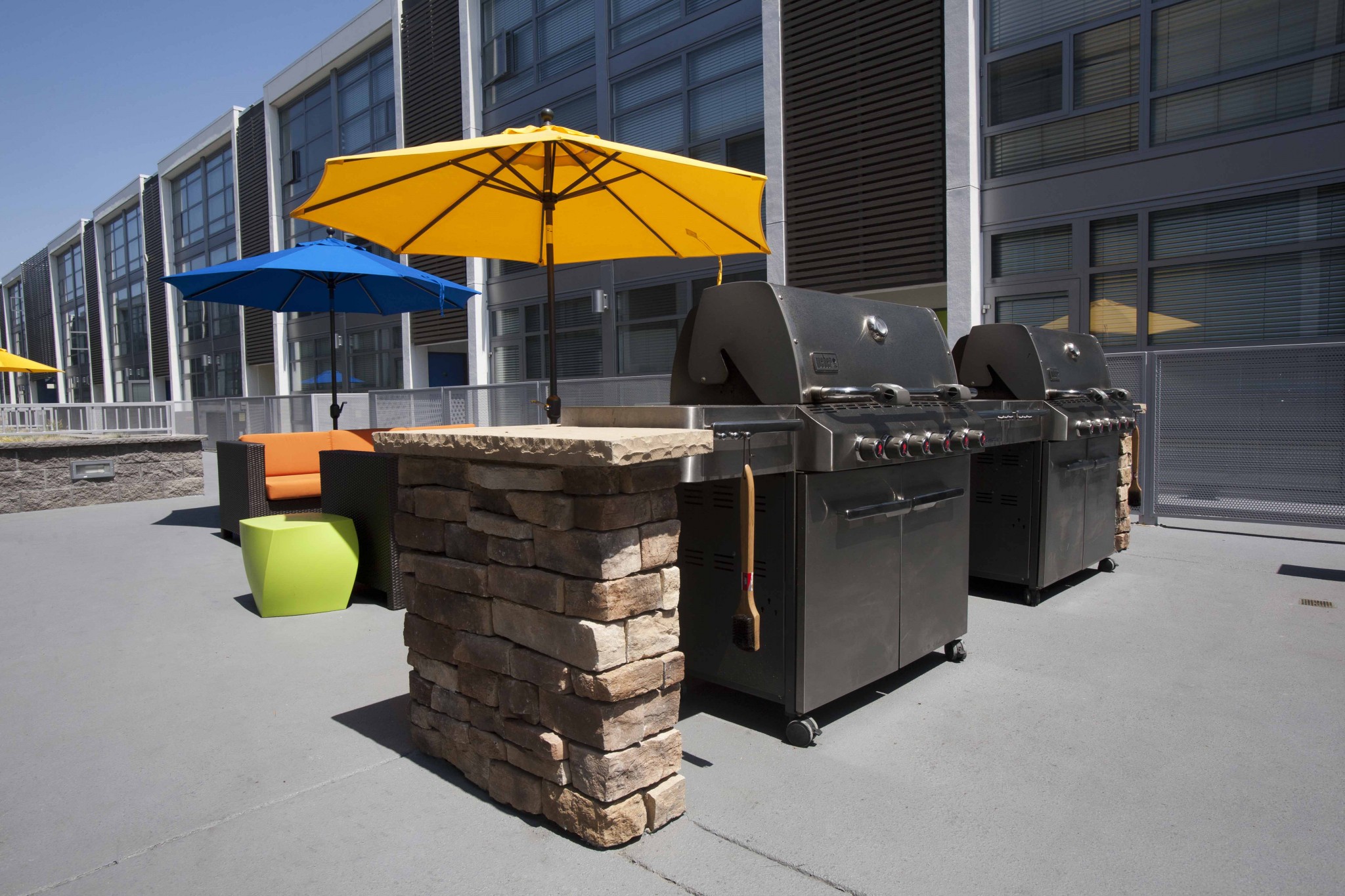 Close up of BBQ grills in the courtyard. with umbrellas in the background.