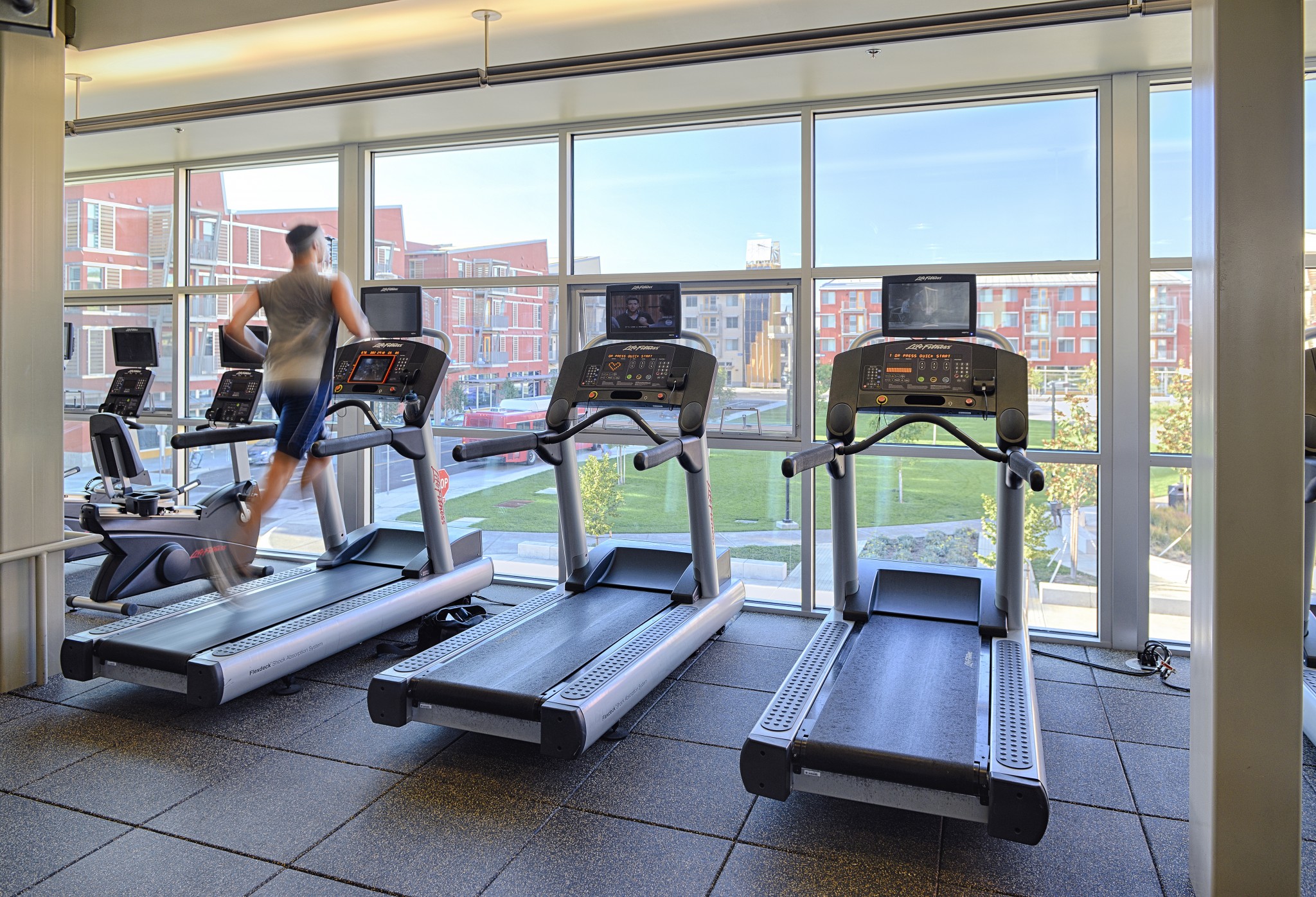 Treadmills in front of large windows with views of other apartment buildings across the way.