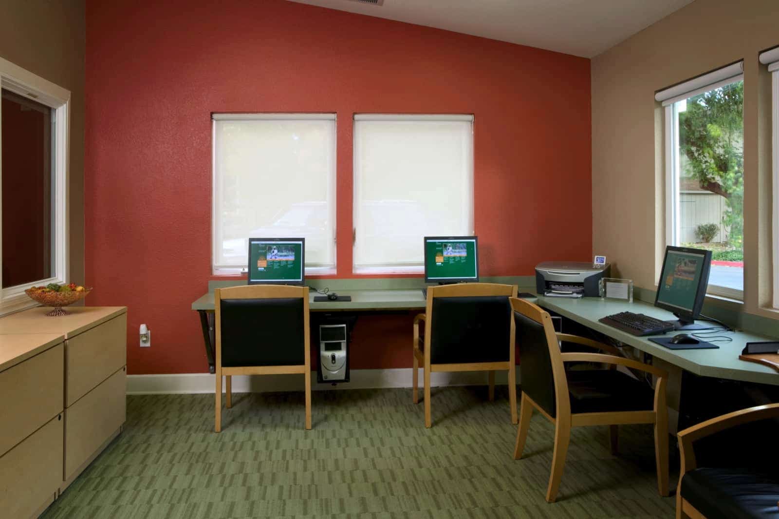View of 3 computer stations and a printer in a business center.