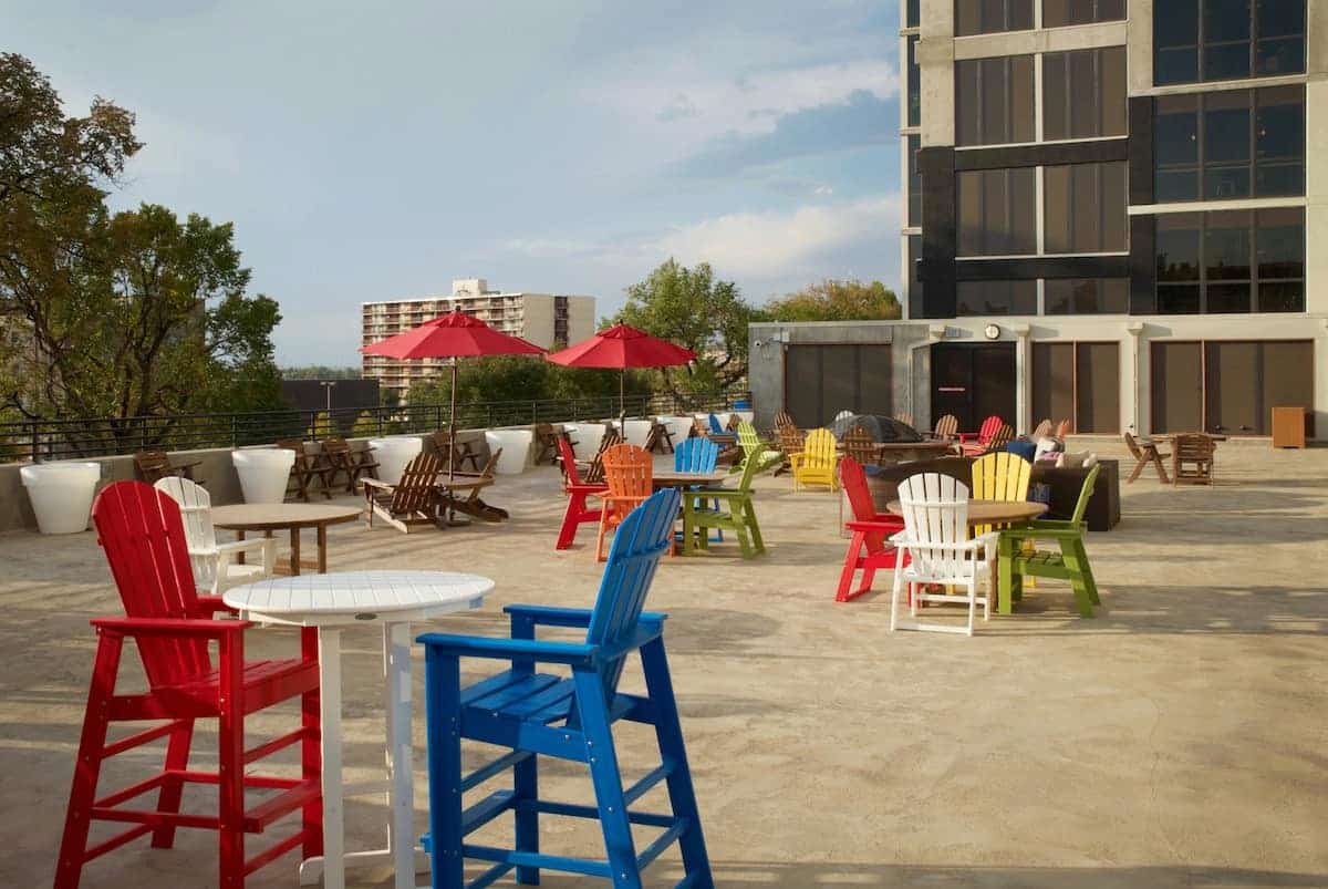 Roofdeck with adirondack chairs and barstools, tables, and umbrellas.