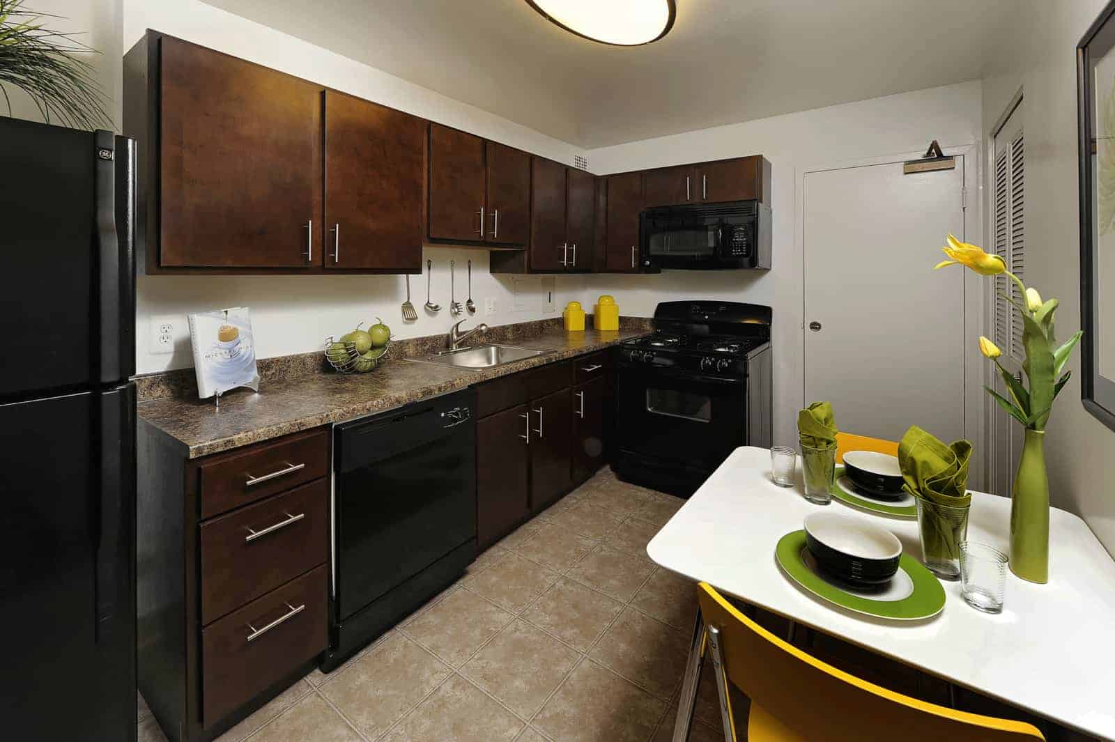 Interior of kitchen with black appliances and brown cabinets.