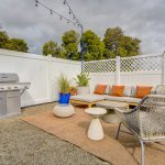 Apartment exterior sitting area with low couch, BBQ and latticed fence