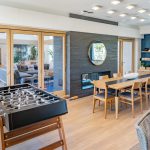 Interior with foosball table, large table and chairs, and fireplace with french doors to another room with couches