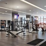 Interior of well appointed gym with city views through wall of windows